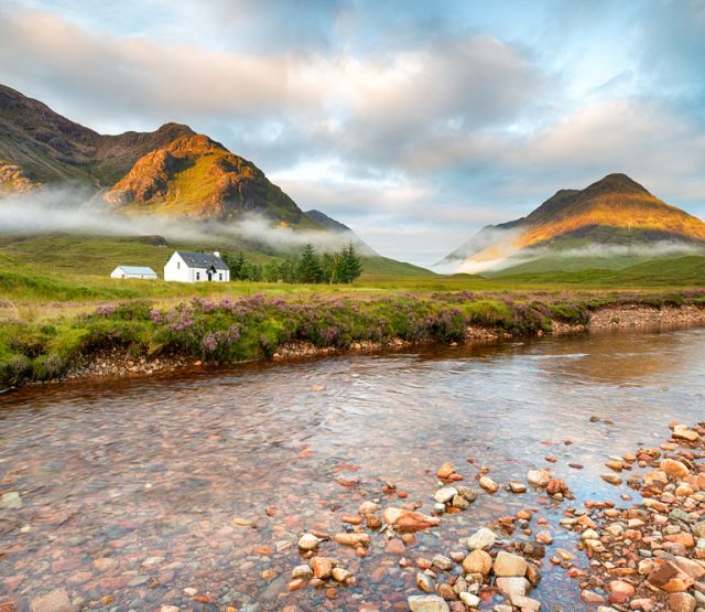 Early morning sun lights the mountain tops at Glencoe in the Scottish Highlands