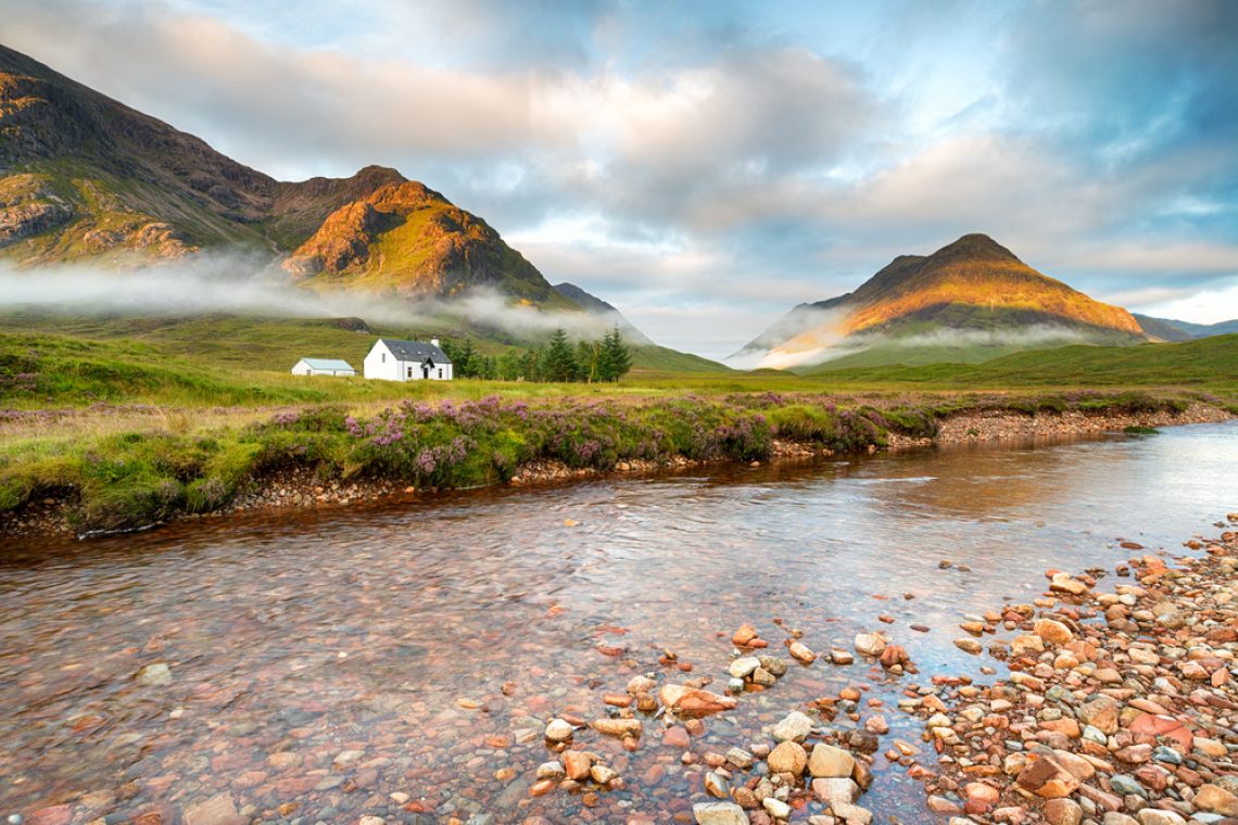 Early morning sun lights the mountain tops at Glencoe in the Scottish Highlands